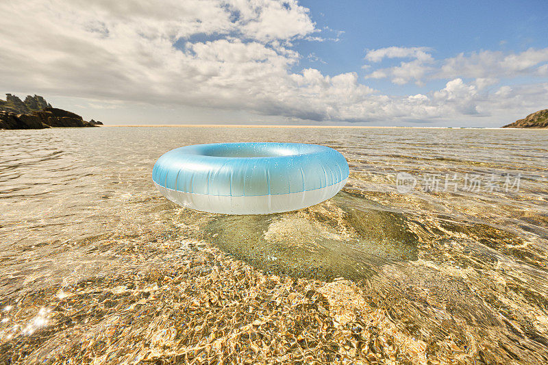 淡蓝色的橡胶圈漂浮在浅水清澈的海面上，在Pedn Vounder海滩，康沃尔在一个田园诗般的阳光明媚的六月天。